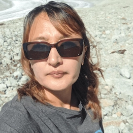Portrait of Nazyerke in sunglasses on a rocky mountain slope