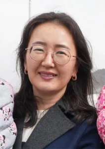 Portrait of Janyerke smiling, in round glasses and a dark coat