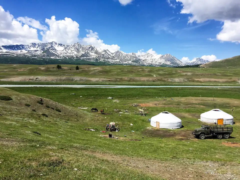 A nomadic family's ger camp beneath the snowy Altai Tavan Bogd peaks