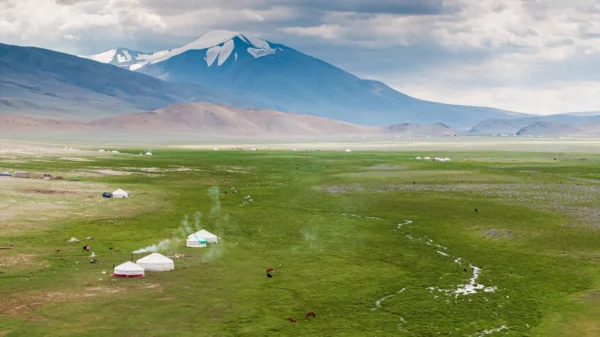 Snow-capped Tsambagarav Mountain above a green valley with nomad gers and grazing horses